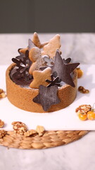 Delicious chocolate tart decorated with star and leaf cookies, walnuts, and cape gooseberries on a marble background. Perfect for holiday dessert, bakery presentation, or festive food photography