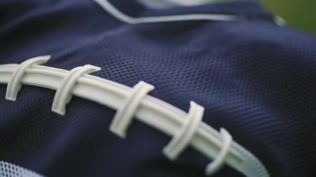 A close-up view of a dark blue sports jersey with white lacing details, highlighting the fabric texture.