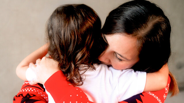 Latin mother hugging her toddler daughter during Christmas season