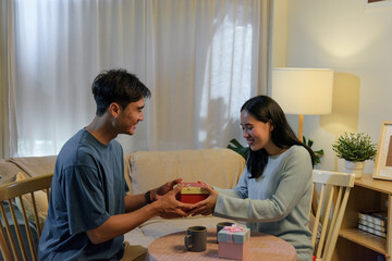 Happy young couple shares loving romantic moment at home, man gives woman special valentine day...