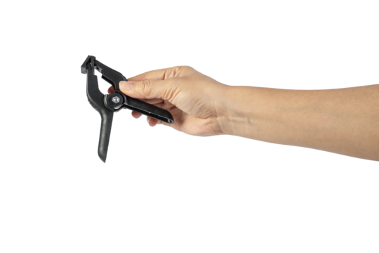 A studio shot of a black plastic spring clamp in hand isolated on a transparent background
