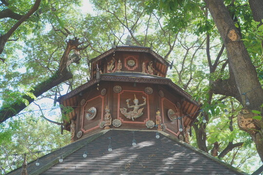 Traditional Thai Wooden Pavilion Roof and Carvings Surrounded by Trees