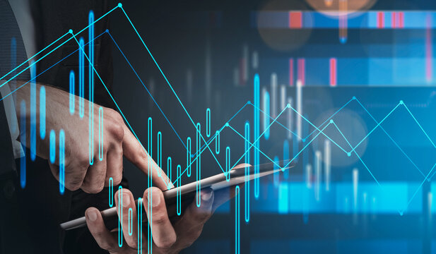 Businessman holding tablet with glowing financial data graphics overlay, futuristic style, on dark blue background, concept of digital investments - Powered by Adobe