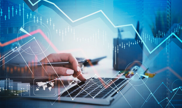 Hand using laptop with financial graphs and candlestick charts overlay, creative digital style on office desk background, concept of business analytics