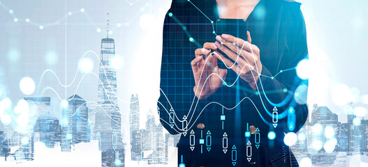 Woman in business attire using smartphone, abstract financial charts over modern city background, creative concept of digital economy and analytics