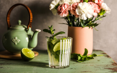 Illustration of refreshing mojito drink with lime and mint next to a teapot