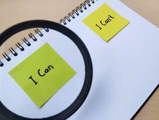 Hand written message i can or i can't on note paper with magnifying glass as self esteem building concept	
