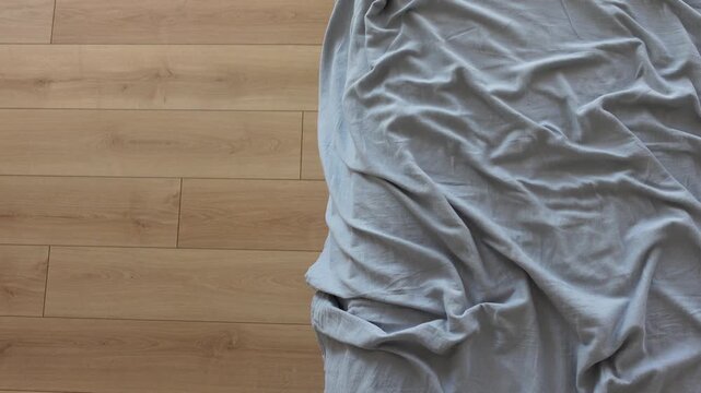 Morning light brightly illuminates rumpled gray sheets