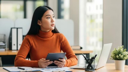Young asian businesswoman using tablet and working on laptop in office - Powered by Adobe