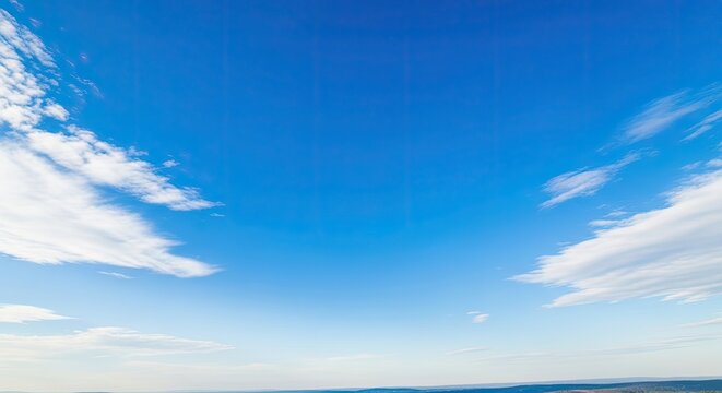 A vast, clear blue sky with scattered white clouds, showcasing the natural beauty of the environment. - Powered by Adobe