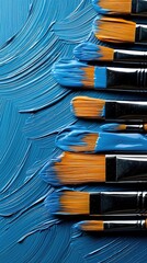 Close-up of paintbrushes covered in blue paint, resting on a textured surface of blue paint, creating an artistic composition.