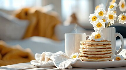 A stack of pancakes with a cup of coffee and flowers on a table, creating a cozy morning scene indoors.