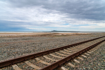 Fototapeta premium Railway tracks and the Bolshoe Bogdo Mountain with the salt lake Baskunchak in the distance on a summer day, Akhtubinsky district, Astrakhan region, Russia
