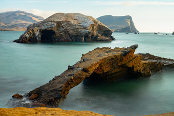A rocky shoreline with a bridge over a body of water