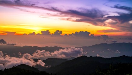 Mountain range silhouettes beneath a vibrant, colorful sunset