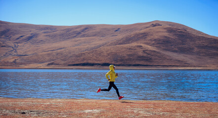 Ultra marathon runner running at winter high altitude lakeside, Tibet