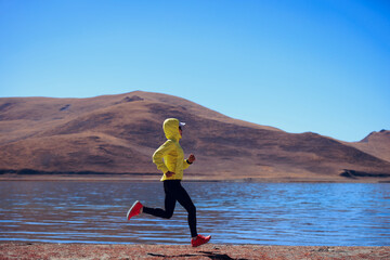 Ultra marathon runner running at winter high altitude lakeside, Tibet