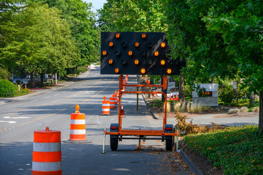 Arrow board used to direct traffic around temporary lane closure, move over lighted road sign with arrows, suburban traffic control
