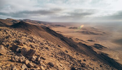 Desert Landscape with Rocky Mountain Slopes Under Cloudy Sky at Sunrise