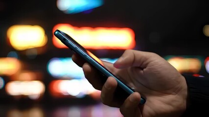Person using a smartphone at night with blurred city lights in the background - Powered by Adobe