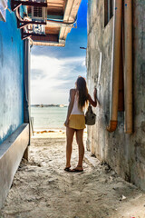Woman gazing at the ocean from a narrow alley in El Nido, Philippines