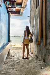 Woman exploring El Nido, Philippines, looking out to the ocean from a narrow alleyway