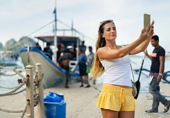 Solo female traveler taking a selfie in El Nido, Philippines, near a boat