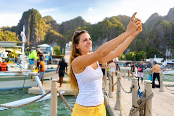 Woman taking a selfie in El Nido, Philippines, with beautiful scenery in the background