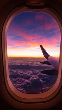 Airplane window view of a vibrant sunset over clouds