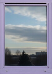 Fototapeta premium Lilac window reflecting sky and city silhouettes evokes calmness