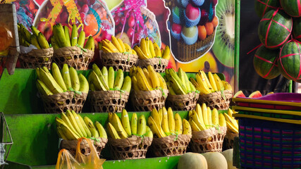 Ripe bananas displayed in woven baskets on tiered shelves at a colorful market stall.