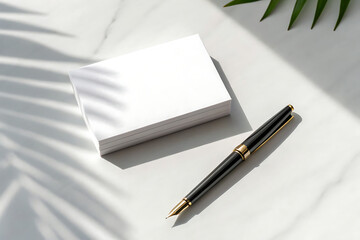 Minimalist flat lay of a blank white card and elegant pen with palm leaf shadows