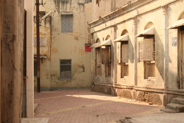 Fototapeta premium Historic architecture in an old Indian city. Features ornate facades, arched windows, weathered walls, and the characteristic streetscape of a traditional neighborhood.
