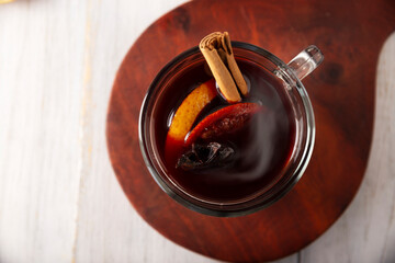 Hot wine or Christmas mulled wine with orange, cinnamon, star anise, clove, nutmeg and other ingredients on a wooden rustic table. Traditional hot drink at winter time and Christmas holidays.