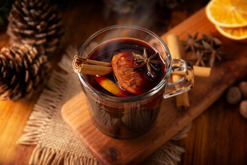 Hot wine or Christmas mulled wine with orange, cinnamon, star anise, clove, nutmeg and other ingredients on a wooden rustic table. Traditional hot drink at winter time and Christmas holidays.