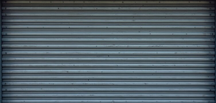 Grey metal roller shutter door creates industrial background. Striped steel surface of closed garage gate forms abstract texture. Weathered iron panel horizontal line pattern, simple urban wallpaper. - Powered by Adobe