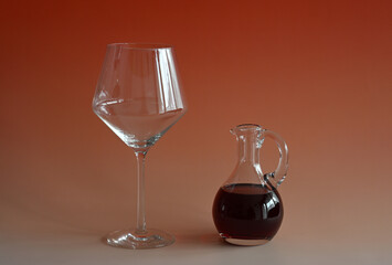 Glaskaraffe mit Rotwein und ein Rotweinglas vor einem bunten Hintergrund