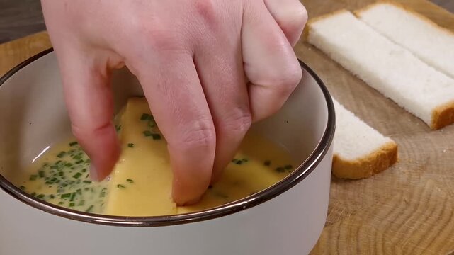 Dipping white bread slices into egg and chive mixture and frying in hot nonstick pan for french toast