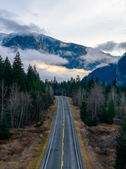 Fototapeta premium Long Winding Mountain Road Through Dense Forests and Misty Valleys in British Columbia, Canada