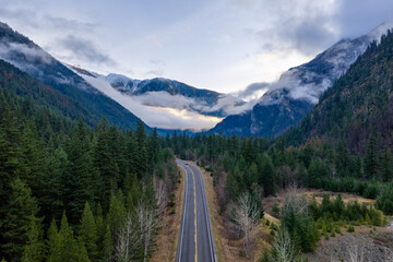 Fototapeta premium Scenic Mountain Road Through Conifer Forest Toward Snow-Capped Peaks in BC, Canada