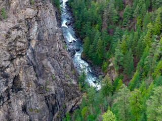 Obraz premium Rugged Canyon and River Gorge Surrounded by Evergreen Forests and Towering Cliffs in BC, Canada