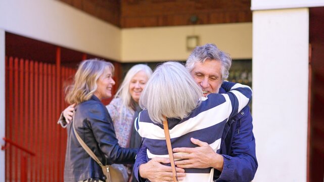 Senior friends greeting and hugging each other outdoors - Powered by Adobe