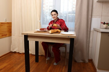 Woman making sandwich while sitting at kitchen table