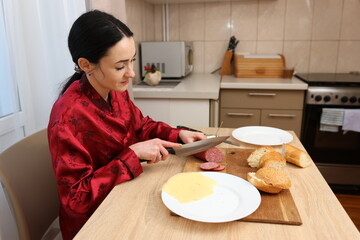 Woman making sandwich while sitting at kitchen table