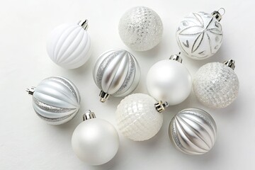 Collection of elegant white and silver Christmas ornaments scattered on a white surface