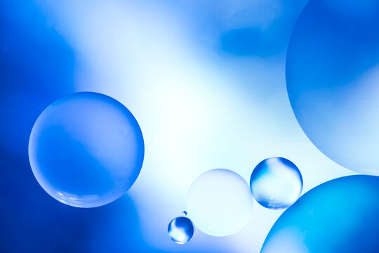 Abstract macro photography of blue liquid spheres and bubbles floating in water with soft light and bokeh effects