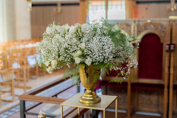 Elegant floral arrangement with white roses and baby’s breath in a church setting during a wedding ceremony