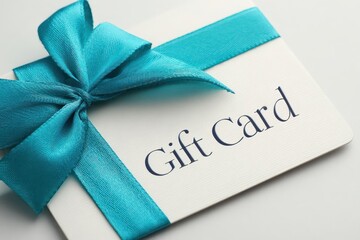Elegant cream colored gift card tied with a bright turquoise satin ribbon and bow on a white background
