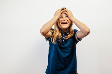 Child laughing with hands on head joyfully.