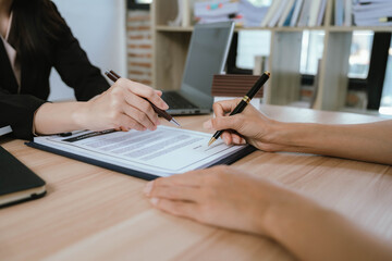 A real estate agent presenting a house model and discussing property details with a client during a contract meeting.